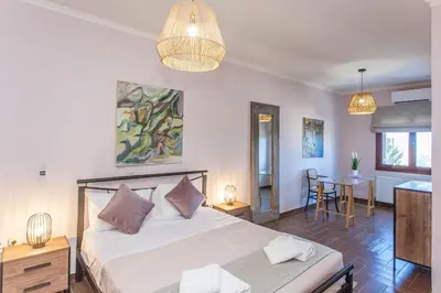 a bedroom with a bed and a table with chairs at Sounds Of The Mountain Chania in Varípetron
