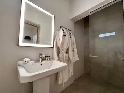 a bathroom with a sink and a mirror and a shower at Perla Coco Jacuzzi Suites in Chania Town