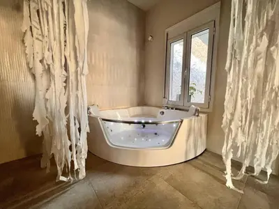 a white tub in a bathroom with a window at Perla Coco Jacuzzi Suites in Chania Town