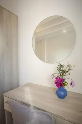 a vase of flowers on a table with a mirror at Rose of Crete in Plataniás