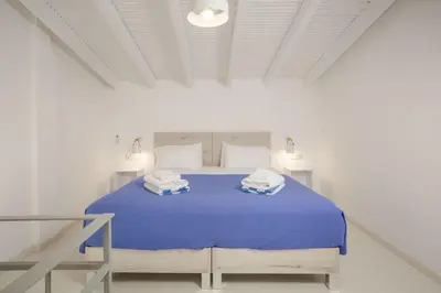 a white bedroom with a blue bed with towels on it at Rose of Crete in Plataniás