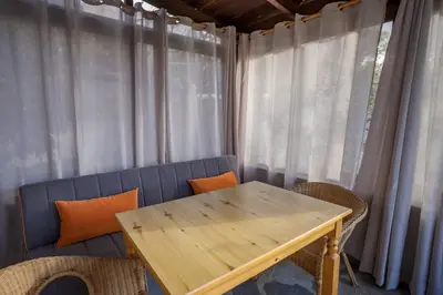 a wooden table and chairs in a room with curtains at Rose of Crete in Plataniás