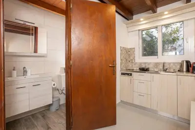 a kitchen with a wooden door leading into a bathroom at Rose of Crete in Plataniás