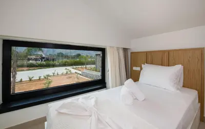 a bedroom with a white bed with a large window at Fairytale Villas in Souda