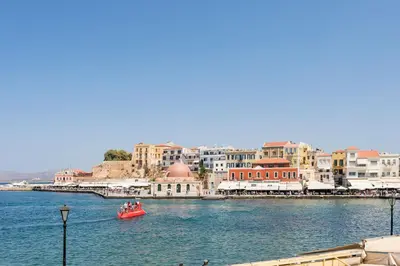 a red boat in a body of water with buildings at Pasifai Residence - Chania old town in Chania Town