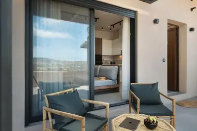 a balcony with two chairs and a table and a bedroom at KOEV slow living in Tsikalariá