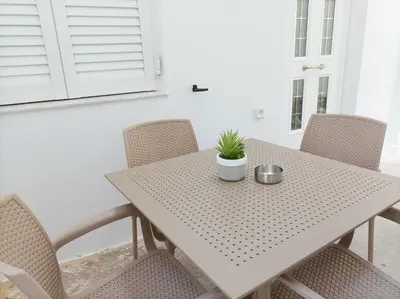 a white table with chairs and a potted plant on it at Amelie Apartment in Palaiochóra