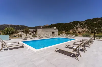 a swimming pool with chaise lounge chairs and a resort at Omalos Village in Omalós