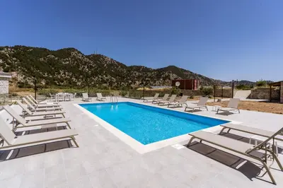 a pool with chaise lounge chairs and a bunch ofitures at Omalos Village in Omalós