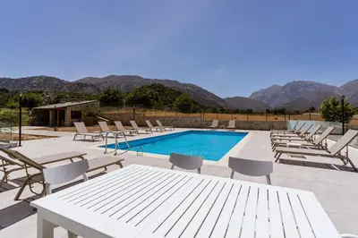 a group of chairs and a pool with mountains in the background at Omalos Village in Omalós