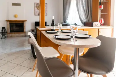 a dining room table with chairs and a table with glasses at Peggy's apartment in Chania in Chania Town