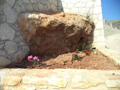 a garden with pink flowers in a stone wall at Falasarna Bay in Falasarna
