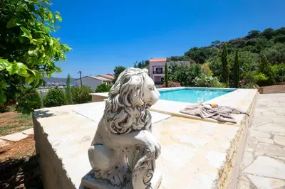 a statue of a lion sitting next to a swimming pool at Villa Leon in Souda