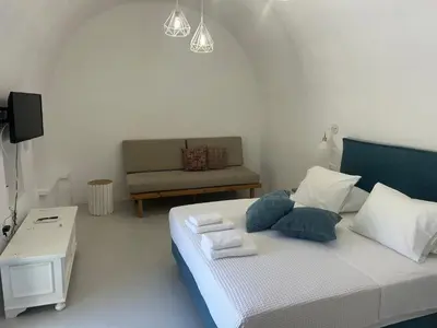 a bedroom with a bed with a chair and a couch at Tholos Cottage in Stérnai