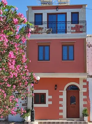 a red building with a balcony and pink flowers at Castello casa in Perivólia