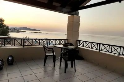 a table and chairs on a balcony overlooking the ocean at 'Sky and Sea 1' Apartment in Kato Daratso