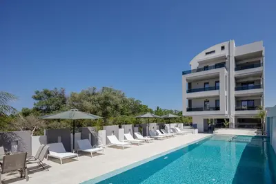 a pool with chairs and umbrellas next to a building at Aurora apartments in Chania Town