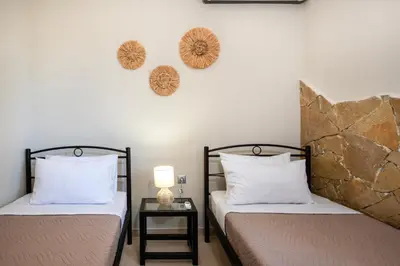 a bedroom with two beds and a table with a lamp at Gabriel apartment with a shared pool close to the beach in Chorafakia