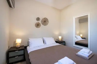 a bedroom with a bed with two lamps and a mirror at Gabriel apartment with a shared pool close to the beach in Chorafakia
