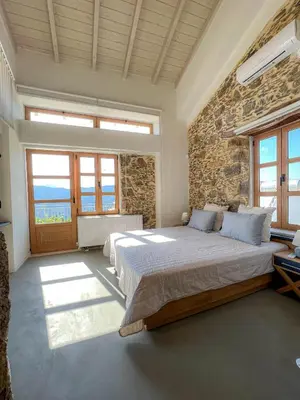 a bedroom with a large bed and a stone wall at The Stone House - Two Bedrooms Maisonette in Avdhoulianá