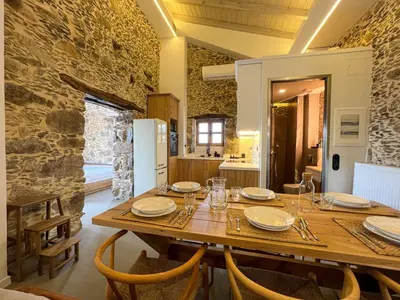 a dining room with a wooden table and a stone wall at The Stone House - Two Bedrooms Maisonette in Avdhoulianá