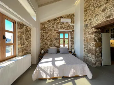 a bedroom with a bed in a stone wall at The Stone House - Two Bedrooms Maisonette in Avdhoulianá