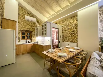 a kitchen with a wooden table and a refrigerator at The Stone House - Two Bedrooms Maisonette in Avdhoulianá