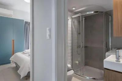 a bathroom with a shower and a toilet and a bed at West City Suite in Chania Town