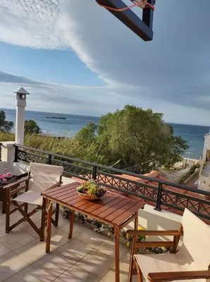 a wooden table and chairs on a balcony with the ocean at Sky & Sea 2 in Kato Daratso