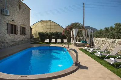 a swimming pool in a yard with chairs and a building at Villa Drapanias Homeleader in Drapaniás