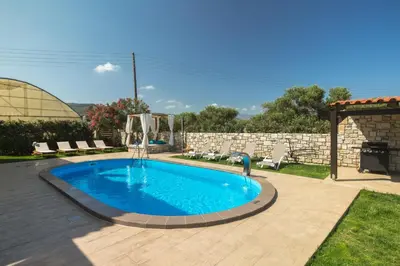 a swimming pool in a yard with chairs and a building at Villa Drapanias Homeleader in Drapaniás