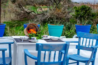 a table with blue chairs and a basket of oranges at Trigono Traditional House in Kalivianí