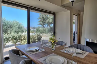 a dining room with a table and a large window at Phaedra by PosarelliVillas in Kounoupidhianá