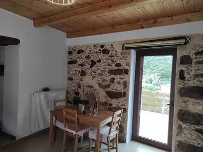 a dining room with a wooden table and a stone wall at Alexander's cottage in Límni
