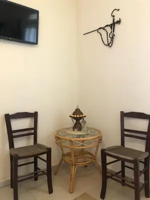 two chairs and a glass table and a tv at ARETI Sea View Mountain Cottage in AmigdhalokeFálion