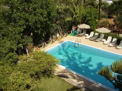an overhead view of a swimming pool with chairs and umbrellas at Summer Lodge in Maleme