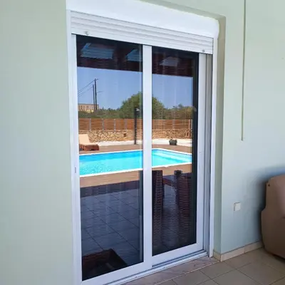 a sliding glass door with a view of a swimming pool at Drosoula Villa 3bdr private swimming pool in Chorafakia
