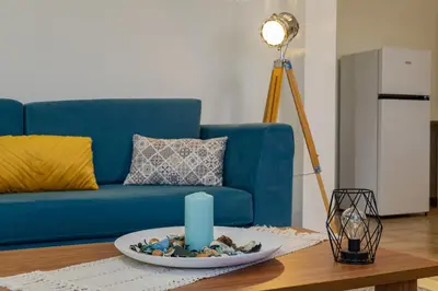 a living room with a blue couch and a candle on a table at Vasiliki house in Daratso