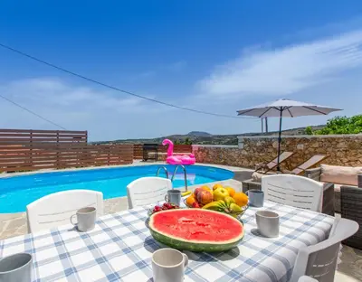 a table with a plate of watermelon and fruit next to a pool at Apokoronas Views Villa in Néon Khoríon