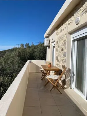 a patio with a table and chairs on a balcony at Koundouros Home in AmigdhalokeFálion