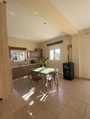 a kitchen with a table and chairs and a stove at Koundouros Home in AmigdhalokeFálion