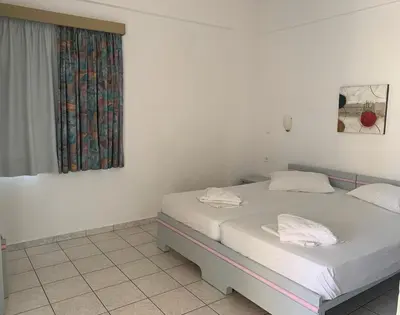 a white room with two beds and a window at Ermis Suites in Plataniás