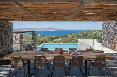 a wooden table and chairs on a patio with a pool at Brand new Villa Eleftheria BY APOKORONAS-VILLAS in Plaka