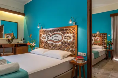 a bedroom with two beds and a blue wall at Aris Boutique Hotel in Palaiochóra