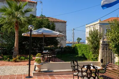 a patio with an umbrella and tables and chairs at Halepa Hotel in Chania Town