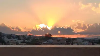 a sunset with the sun setting behind a city at Sun City in Kato Daratso