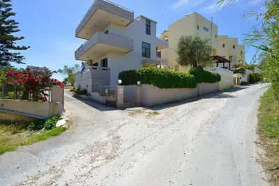 a house on a dirt road next to a driveway at PanDora maisonette with beautiful gardens and pool in Maleme