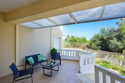 a patio with chairs and tables on a balcony at PanDora maisonette with beautiful gardens and pool in Maleme