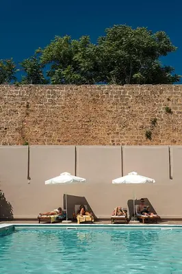 two people laying in chairs and umbrellas in a swimming pool at Kriti Hotel in Chania Town