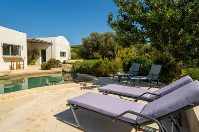 a couple of lounge chairs next to a swimming pool at Villa Lucy by PosarelliVillas in Plataniás